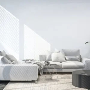 This modern living room embodies calm sophistication with its minimalist design and soft beige palette. Sleek lines and subtle furniture textures create a serene, welcoming vibe, while the round coffee table and light wood flooring add to the sense of tranquility. Thoughtfully chosen decor—an elegant painting and lush indoor plants—infuses warmth and vitality, transforming the space into a true haven for relaxation and comfort.